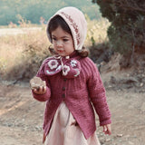 little girl wearing hand knitted scarf with floral embroidery on it, it fits perfectly with her outfit