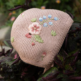 Knitted heart-shaped pouch with floral embroidery on a leafy background