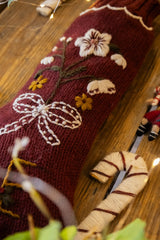 Decorative  sock with floral and bow design on a wooden surface.