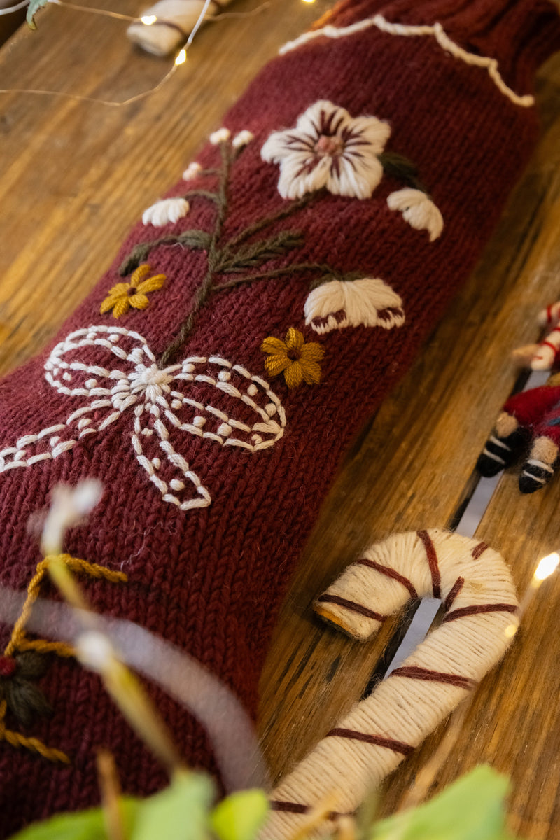 Decorative  sock with floral and bow design on a wooden surface.
