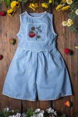 Light blue denim dress with floral embroidery on a wooden surface with flowers around