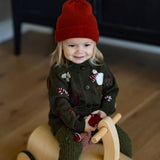 girl wearing red hat and knitted and embroidered holiday goose cardigan in dark green shade