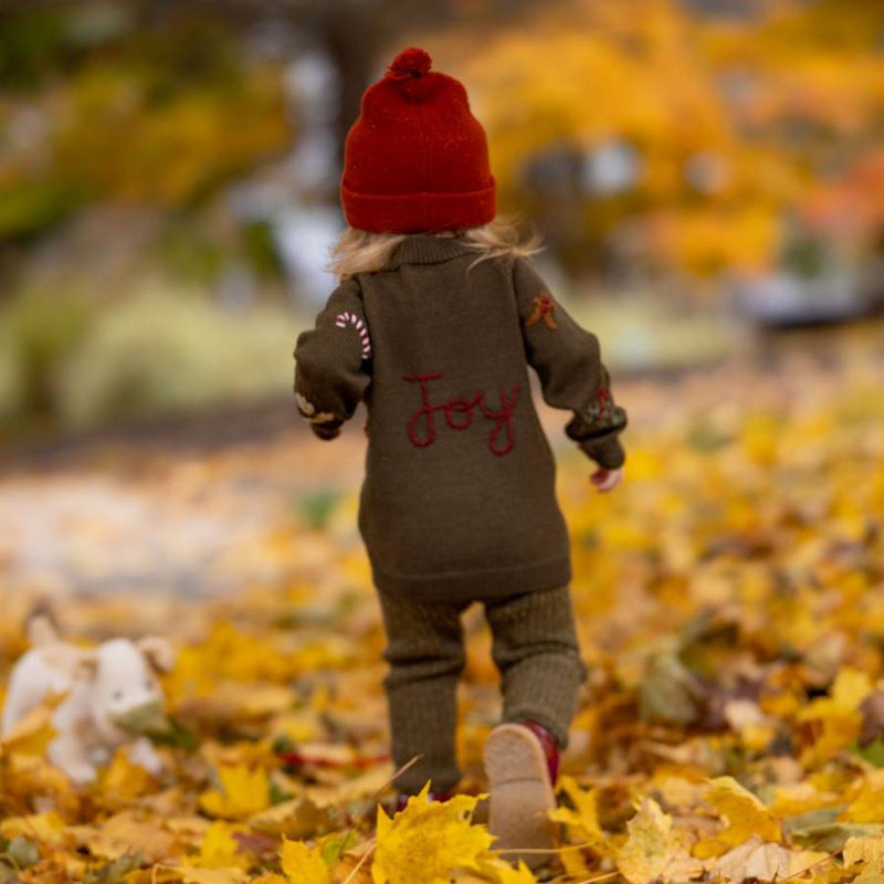 girl wearing red hat and knitted and embroidered holiday goose cardigan in dark green shade