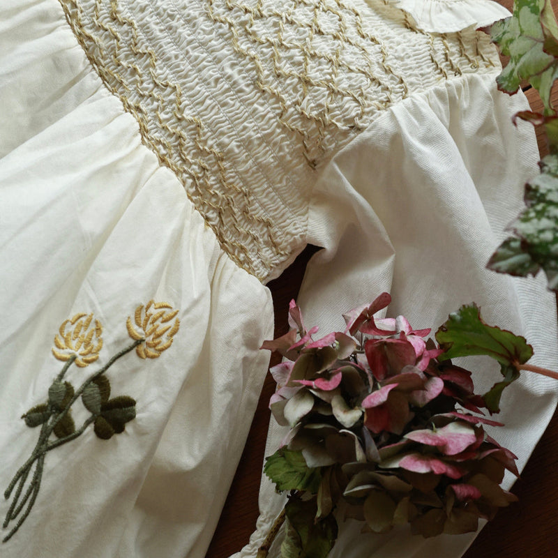 Close-up of a textured white fabric with floral embroidery on a wooden surface