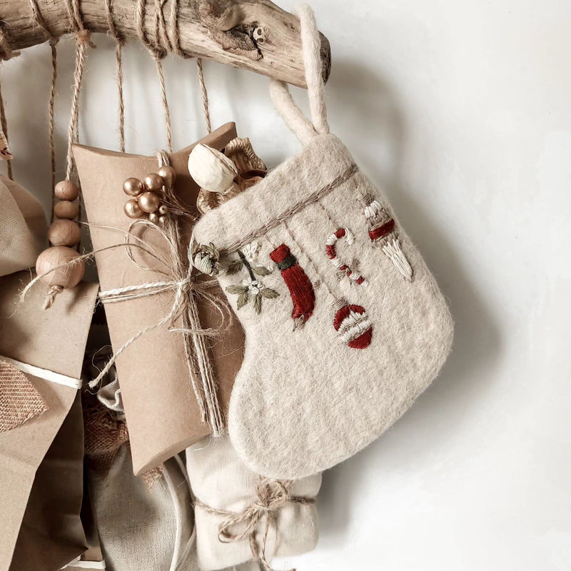 Mini Stocking Garland with intricate embroidery, placed next to decorative gifts and holiday ornaments