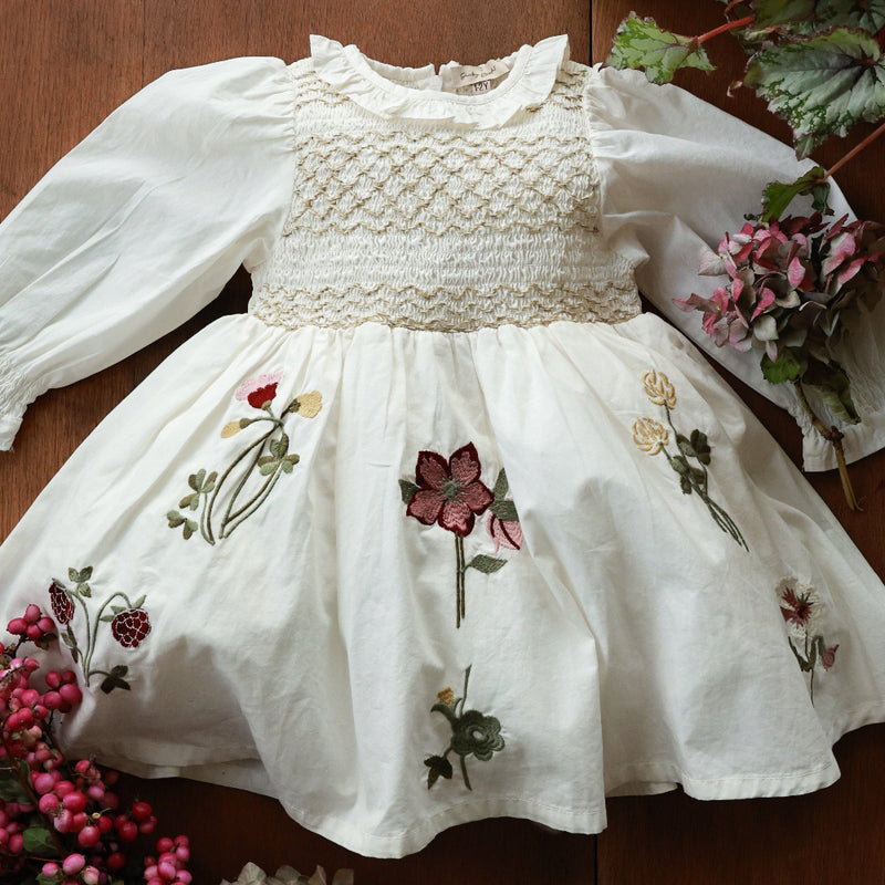 White dress with floral embroidery on a wooden surface