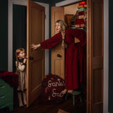 A mother and child in the frame with a red wool Santa sack featuring "Santa's Sack" embroidery prominently visible.