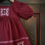 Red dress with patchwork embroidery on a wooden background