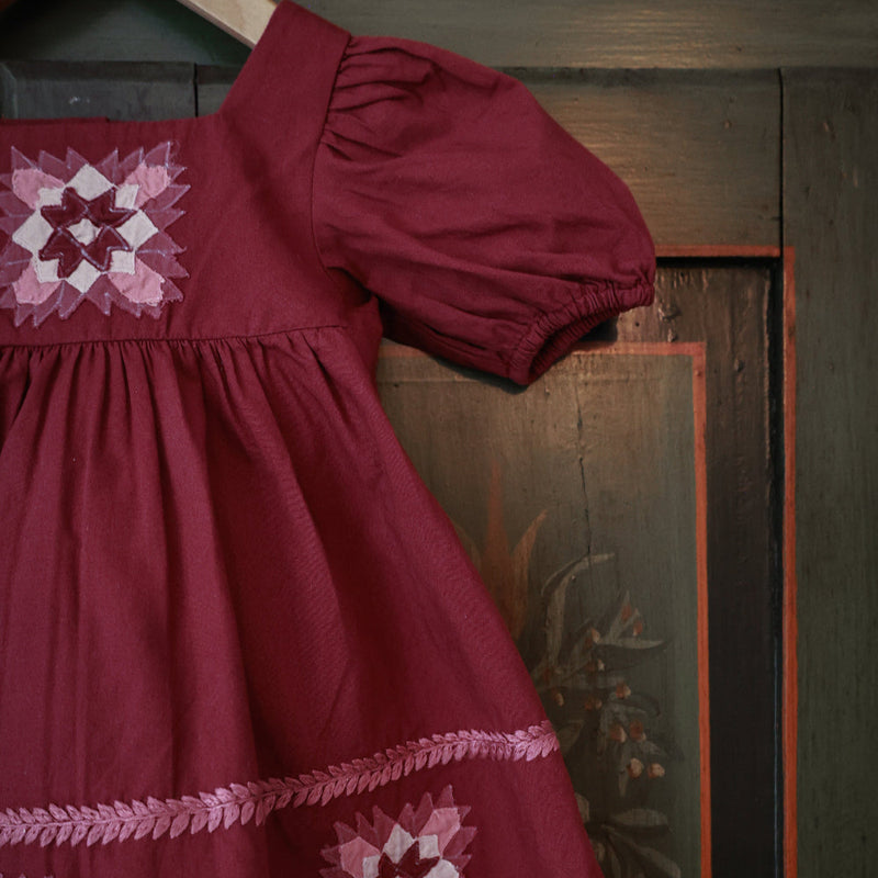 Red dress with patchwork embroidery on a wooden background