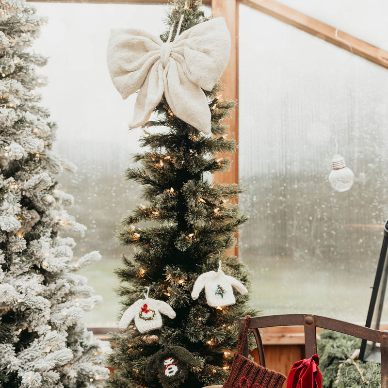 Decorated Christmas tree with stockings and a large white bow in a festive setting.
