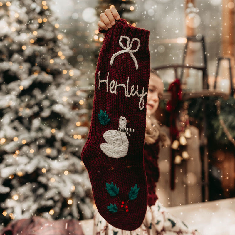 Person holding a personalized Christmas stocking with a festive background