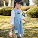 Young girl in a blue dress holding a basket in a garden