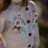 Child wearing a pink embroidered cardigan with floral patterns outdoors