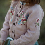 Pink cardigan with floral embroidery on a blurred natural background