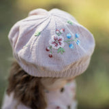 Pink embroidered hat worn by a person with a blurred natural background