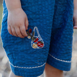 Blue textured dress with a colorful bag design held by a child's hand.
