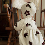 a baby girl wearing white hellebores knitted bonnet and a romper