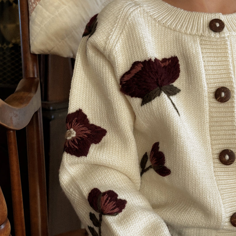 a girl wearing knitted and embroidered hellebores cardigan