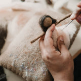 Artisan crafting a pink hand-felted ballerina ornament, showcasing the wool felting process and the delicate attention to detail involved in creating this elegant piece.