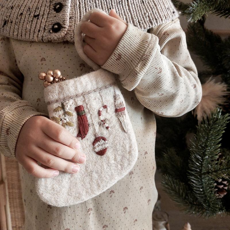 Mini Stocking Garland with intricate embroidery, held in hands with a soft-focus background of festive decor






