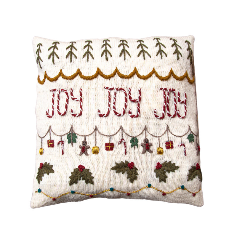 Joy Pillow Cover in Cream White, hand-knitted from 100% merino wool with a wooden button closure, featuring intricate hand-embroidered details and festive JOY design.