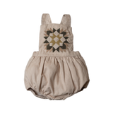 A beige patchwork romper with a geometric pattern in brown shades.