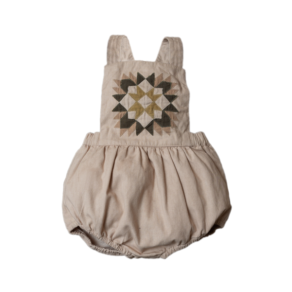 A beige patchwork romper with a geometric pattern in brown shades.