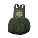 A green romper with a geometric patchwork design on the front.
