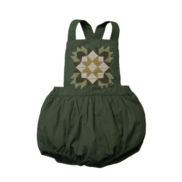 A green romper with a geometric patchwork design on the front.