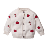 A white wool cardigan with hand-embroidered red apples and wooden buttons for children.