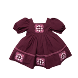 A short-sleeved patchwork dress in purple with floral embroidery, presented against a plain background.