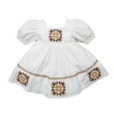 A white short-sleeved patchwork dress with geometric patterns in brown and beige accents, presented against a plain background.