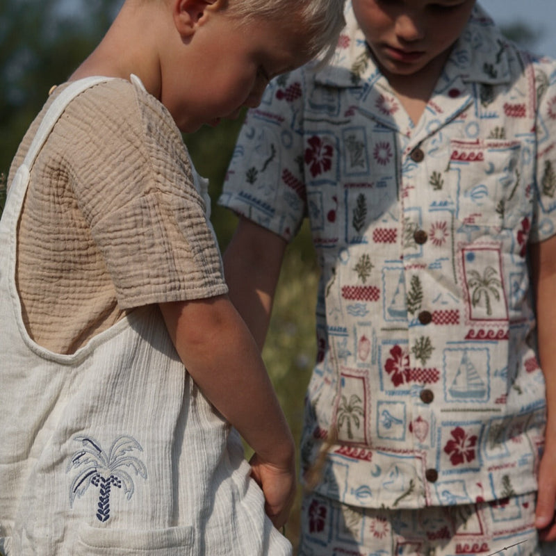 Two children in patterned outfits standing in a field.