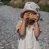Child holding a toy camera outdoors on a gravel path