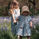 Two young girls in matching dresses standing in a field of flowers.