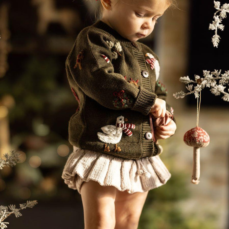 little girl in a christmas outfit featuring our knitted and embroidered holiday goose cardigan in pine color