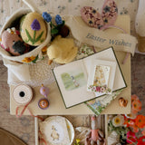 Easter-themed display with eggs, cards, and decorative items on a floral-patterned surface.