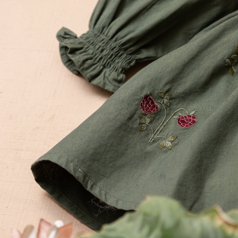close up of green sewn dress with flower embroidery for kids