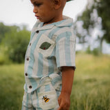 Child wearing the Ladybird Set, with nature and greenery slightly blurred in the background.







