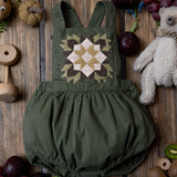 green patchwork romper for kids on wooden background surrounded with fruit and toys