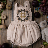 nude patchwork romper for kids on wooden background surrounded with fruit and toys