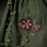 close up of flower embroidery on a green dress for kids