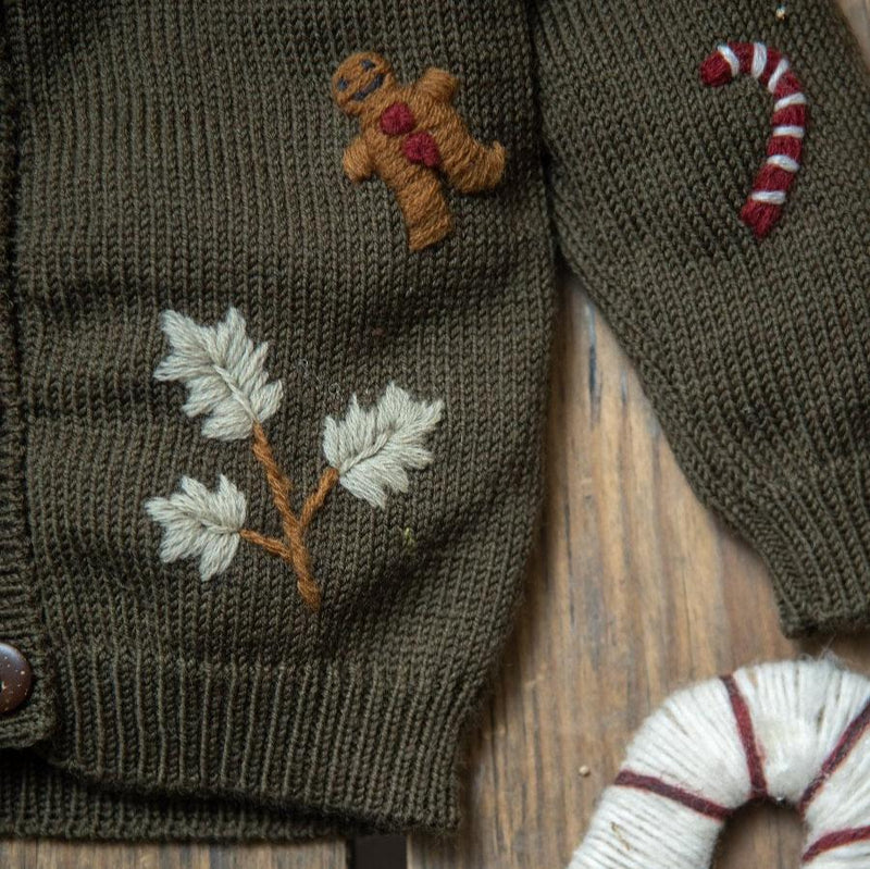 Detail view of the 100% merino wool fabric of the pine green cardigan, illustrating the softness and high-quality craftsmanship of the hand-embroidered designs.
