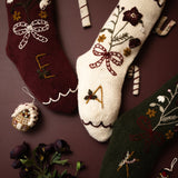 Decorative Christmas socks with floral patterns, candy canes, and small ornaments on a brown background.