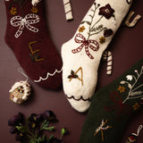 Decorative Christmas socks with floral patterns, candy canes, and small ornaments on a brown background.