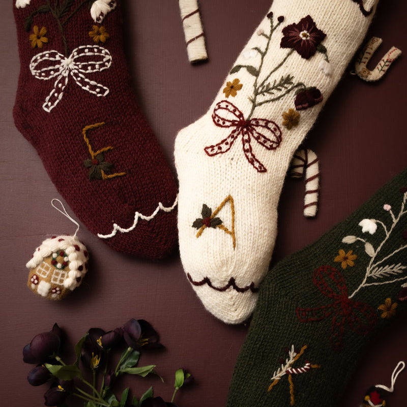 Decorative Christmas socks with floral patterns, candy canes, and small ornaments on a brown background.