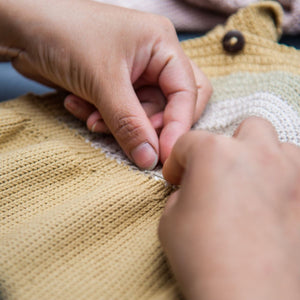 Process of hand-knitting baby romper in our Kathmandu studio