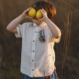 Child holding two lemons over their eyes in a natural setting