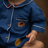 Close-up of a child wearing a blue outfit with white trim and gold buttons.