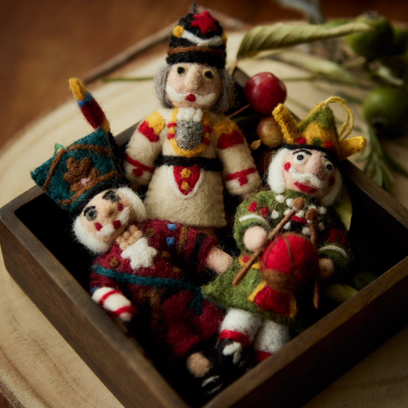 Various Nutcracker ornaments in different colors displayed in a wooden box